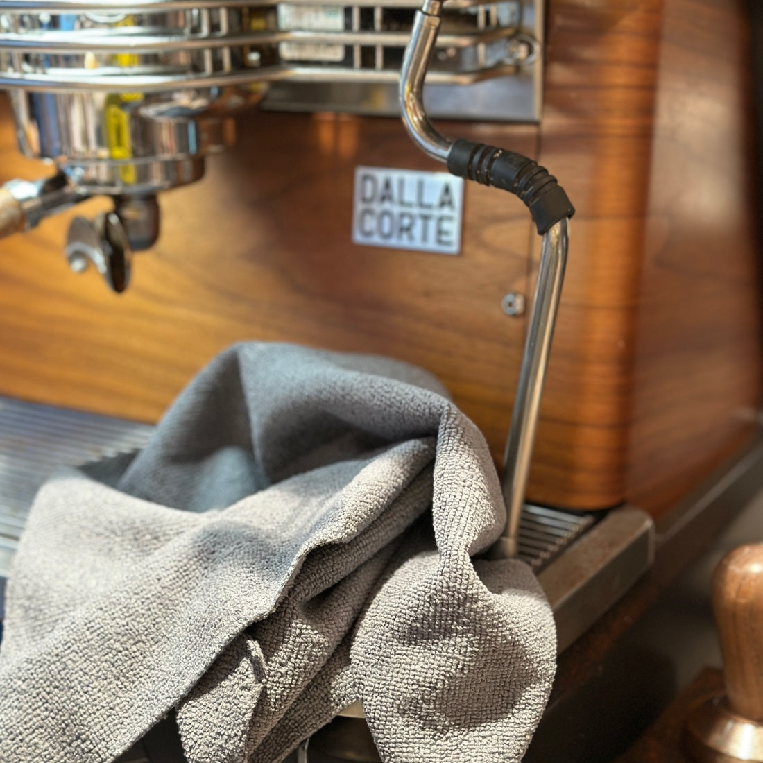 Ein graues Mikrofasertuch von der Rolle im Einsatz beim säubern einer Kaffeemaschine. Sie sind eine langlebig-
ere und hochwertigere Alternative zu Papierhandtuchrollen. Nach Gebrauch können Sie sie zur Wiederverwendung in der Waschmaschine waschen.